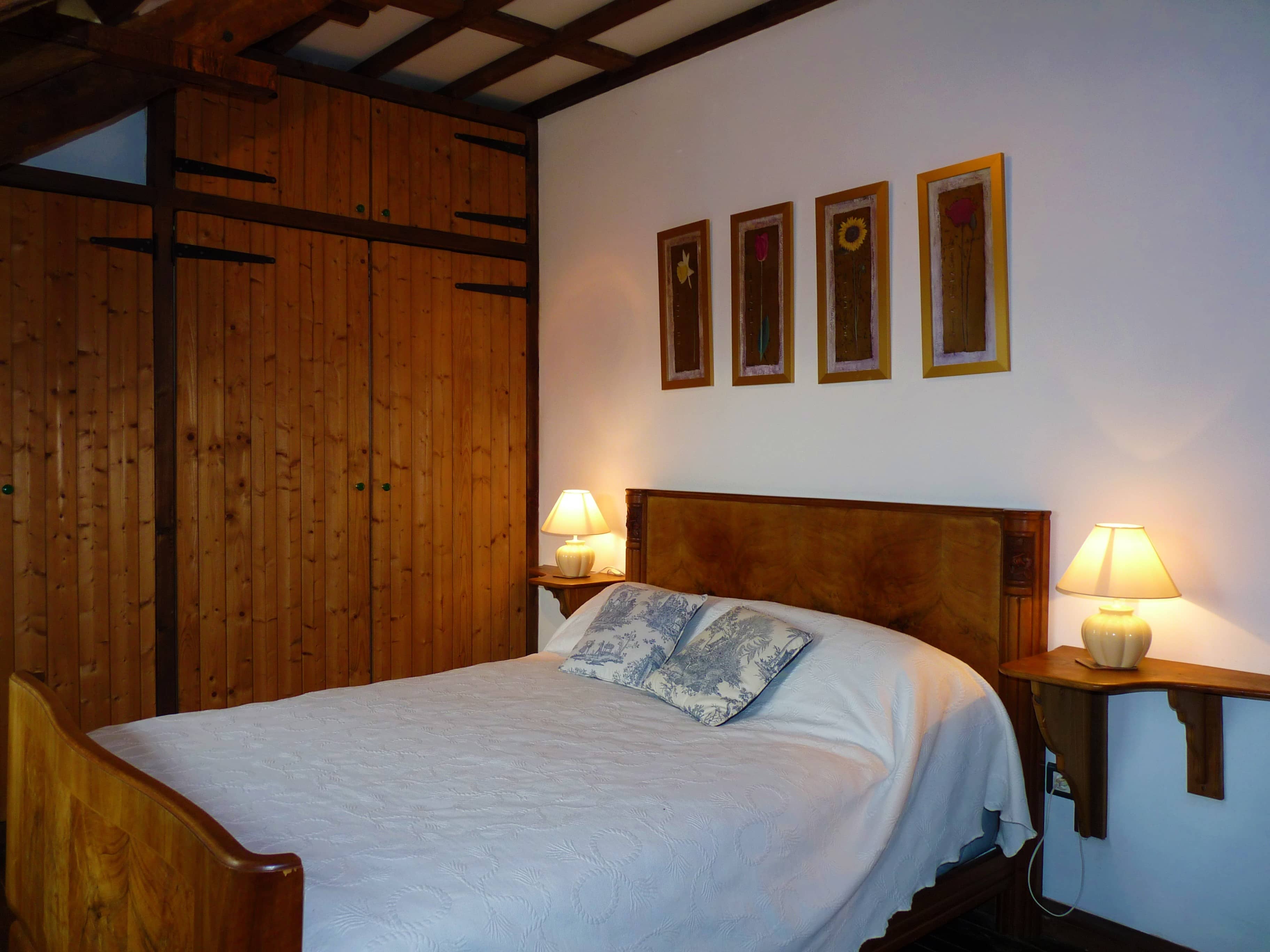 Spacious and comfortable bedroom of La Julerie cottage in Brittany, France, with a king-size bed, elegant rustic decor, a stone fireplace, and a panoramic view of the surrounding countryside. Perfect for a peaceful night's sleep after a day of sightseeing in the Brittany region.